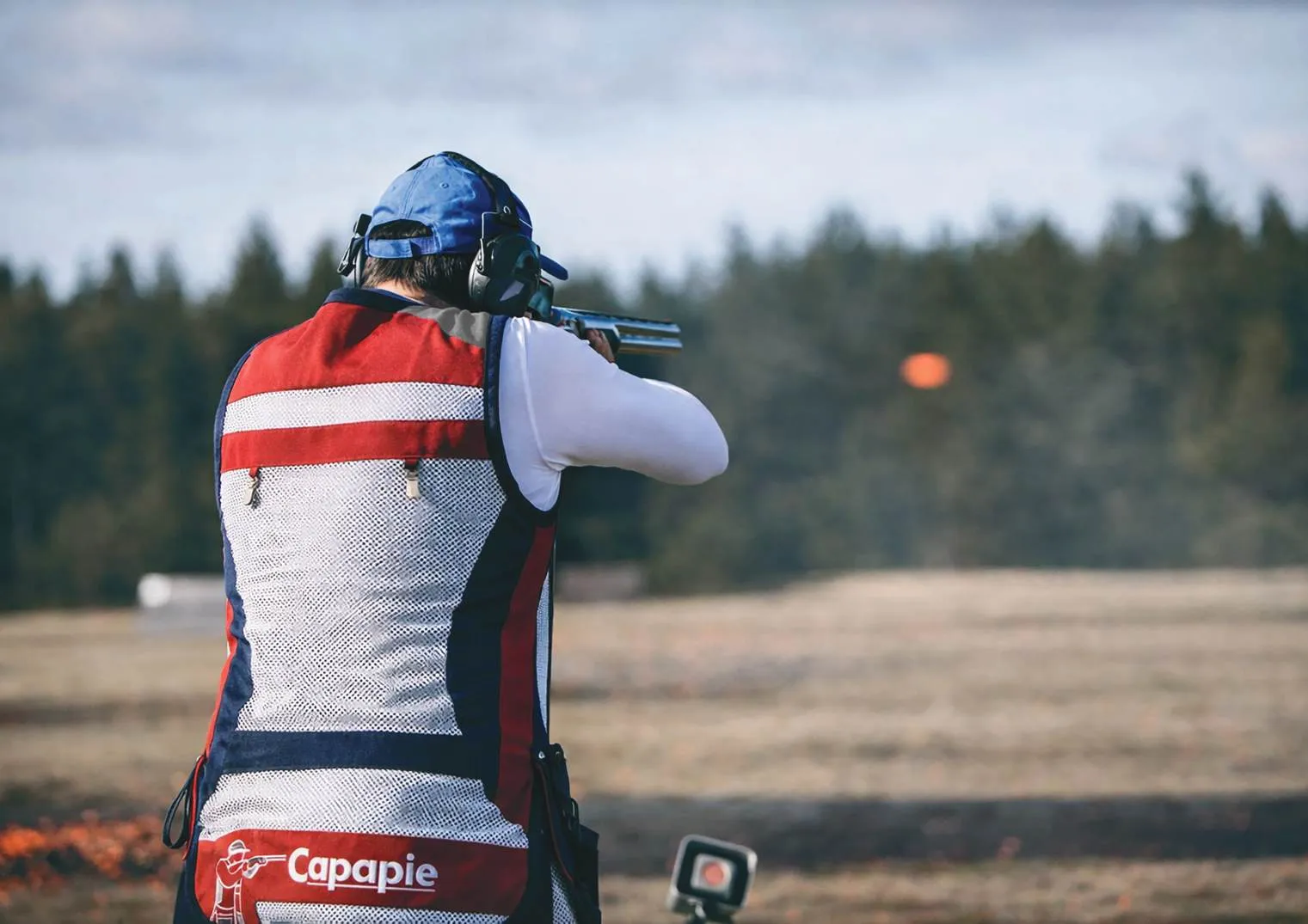 Competitive shotgun shooter in a Capapie vest calling for a target on the trap line